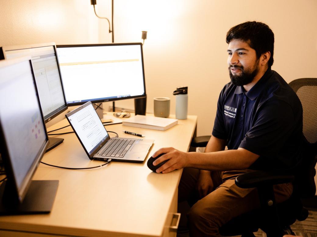 A staff member sits at their desk and works on their computer.