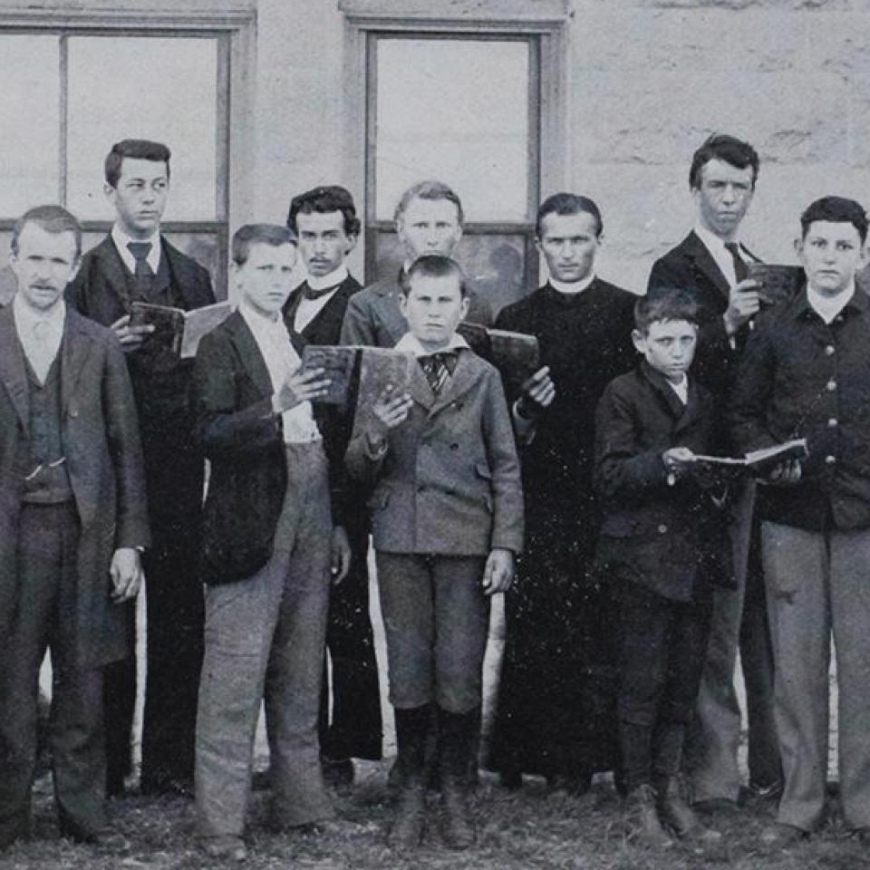 A group of classmates and brothers posing in a makeshift building in 1878 