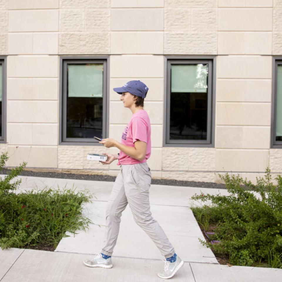 Stella Cunngham walks up a path with windows behind her.