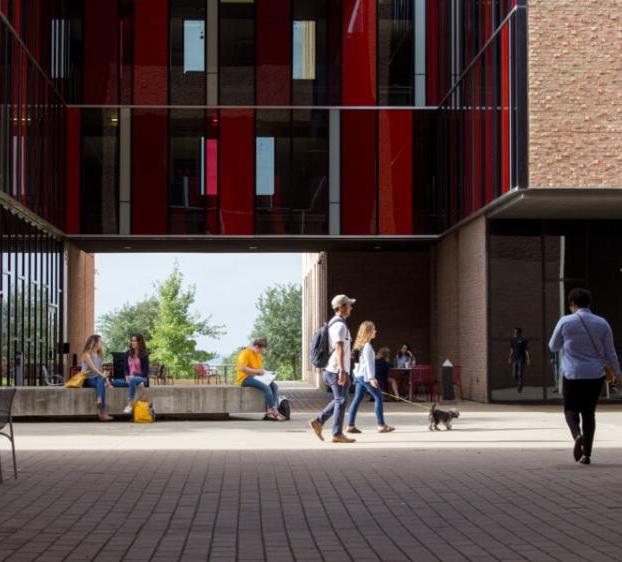 People walk through or sit in the courtyard patio space of The Village.