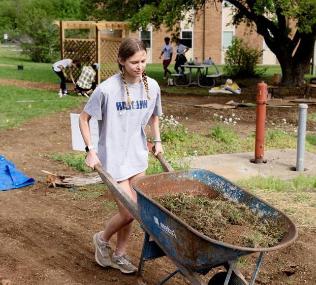 a student at the big event pushing a wheel barrow 