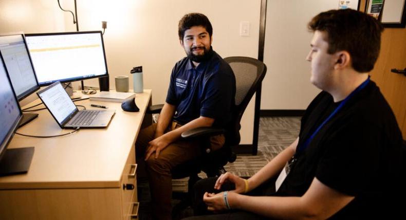 A student meets with a success coach in their office.