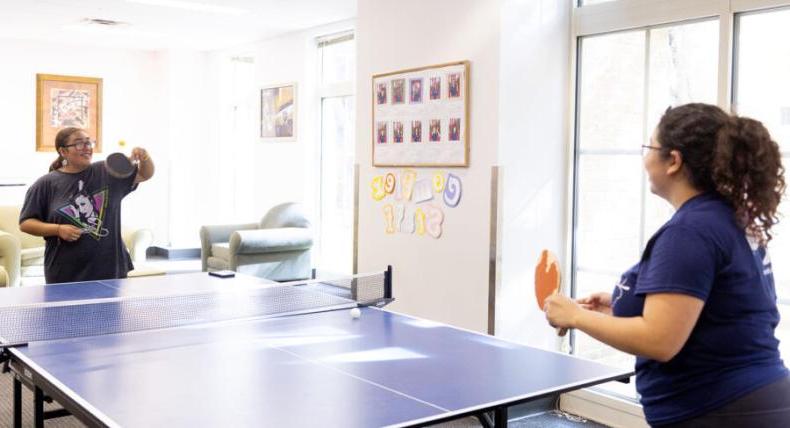 2 students playing ping pong in a residence hall 