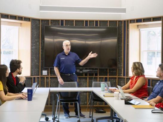 A professor lectures to a small class of graduate students.