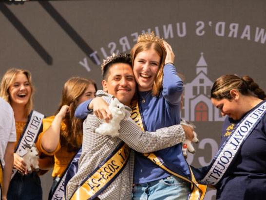 Two students on the homecoming court embrace on stage after being crowned homecoming queen and homecoming king.