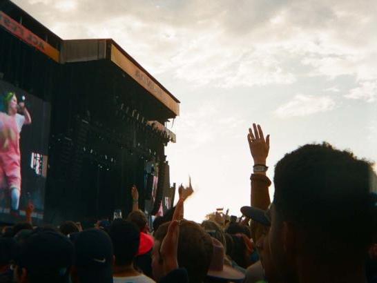 A large crowd in front of a stage where Billie Eilish is singing