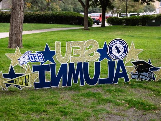 A custom yard sign reading SEU 校友, surrounded by stars, logos and grad caps.